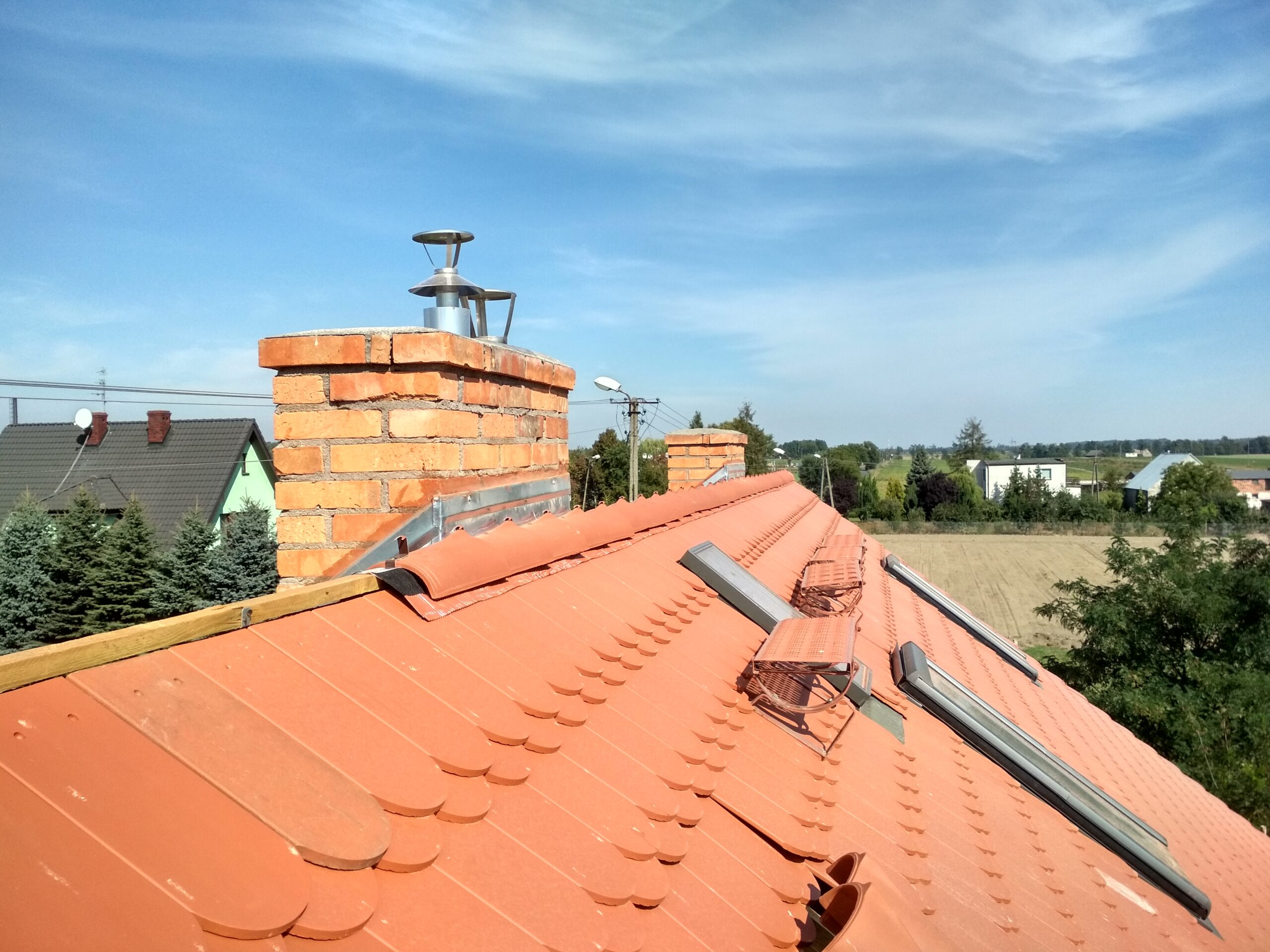 Zbliżenie nowego pokrycia z dachówki przy kominie i stopniach kominiarskich