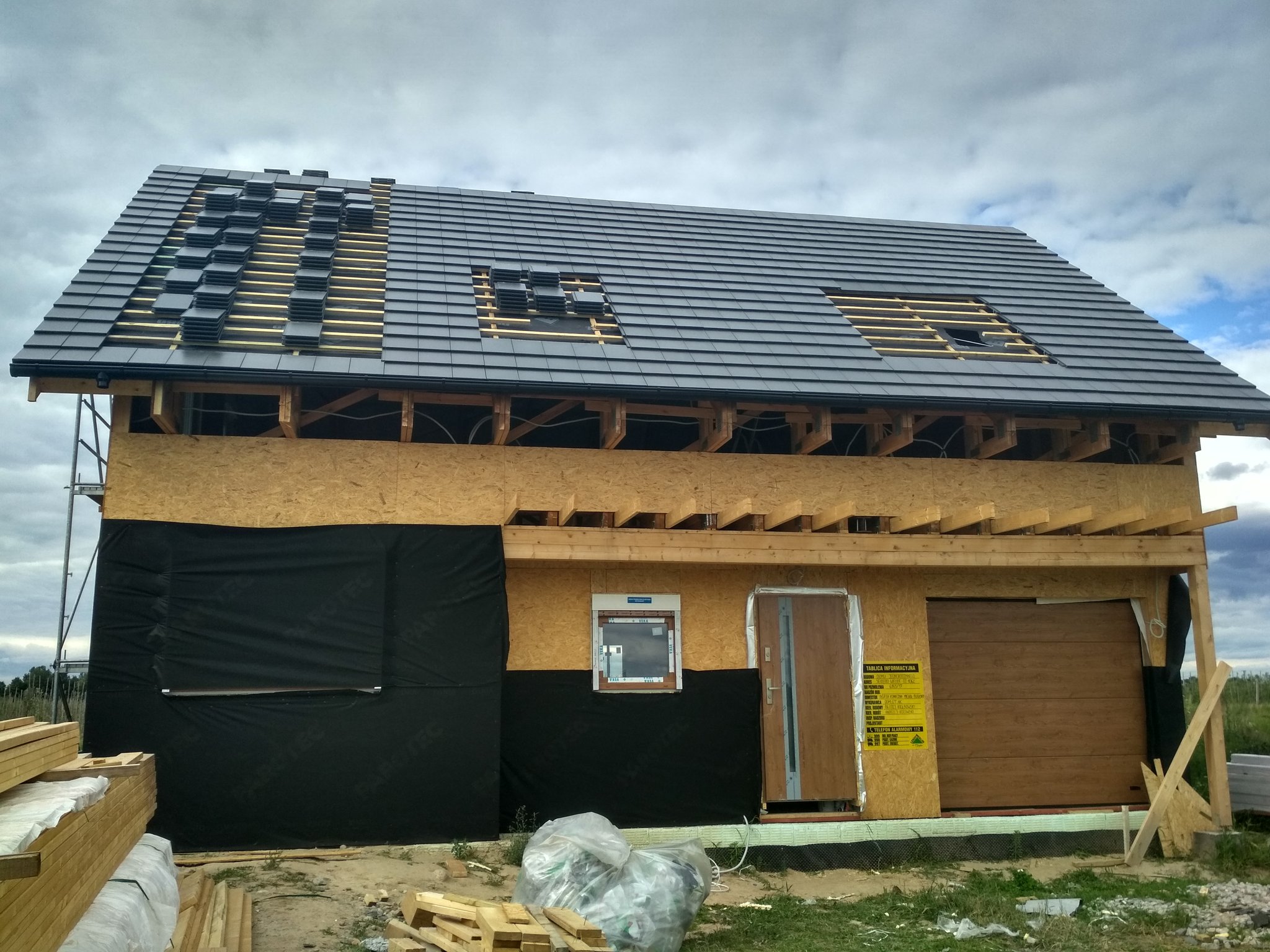 Dach w trakcie krycia grafitową dachówką, otwory pod okna dachowe
