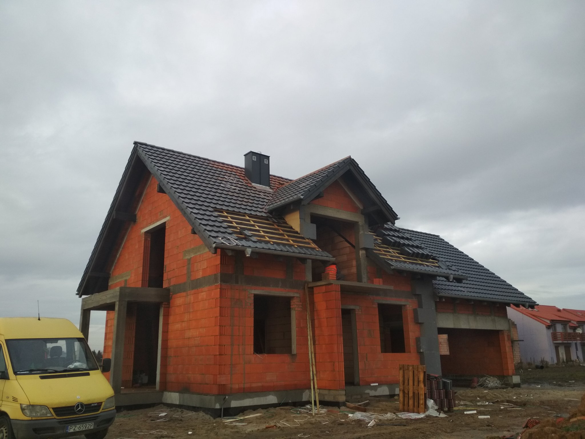 Dom w stanie surowym z dachem pokrytym ciemną dachówką