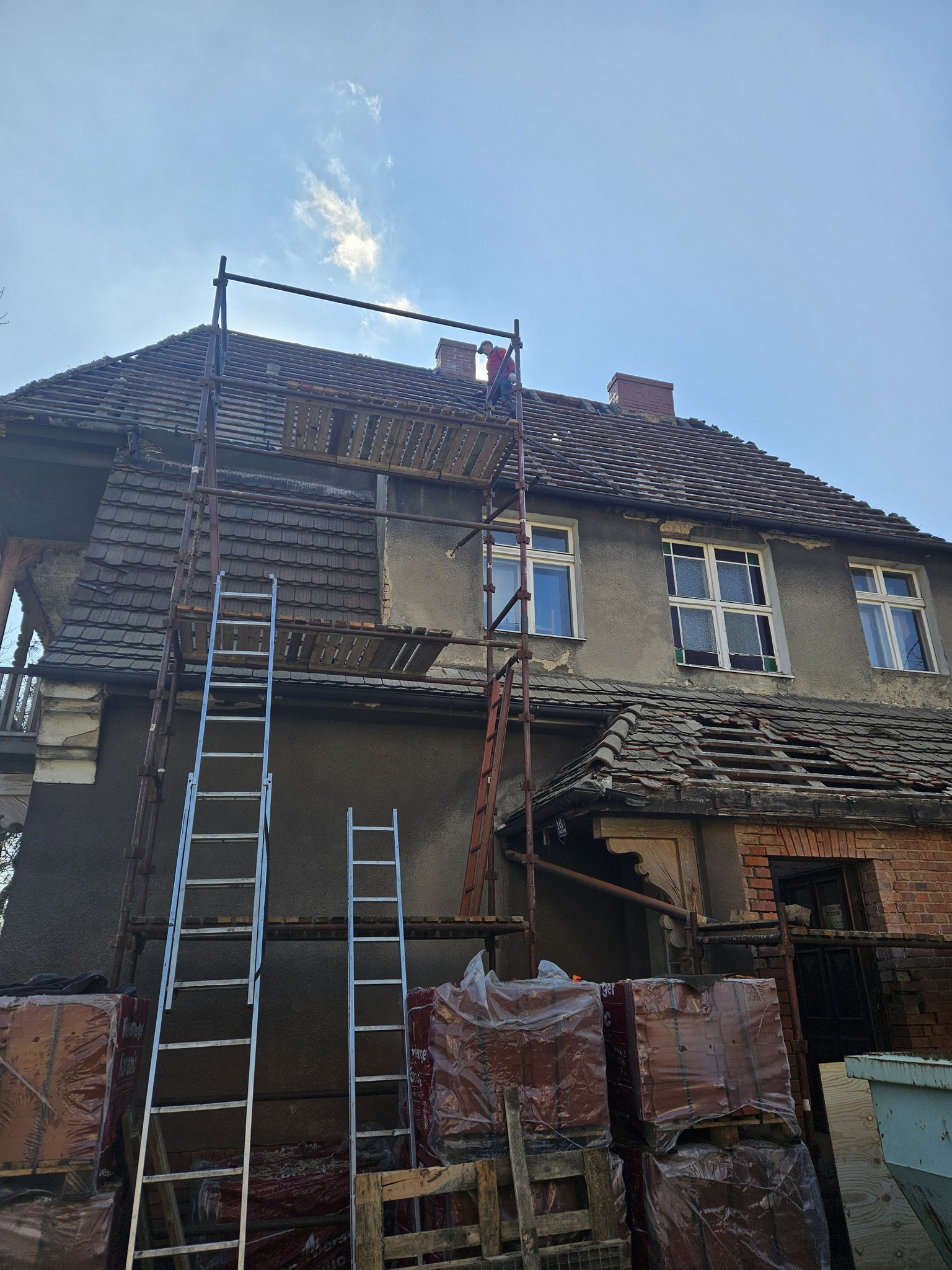 Rusztowania i palety dachówki przy domu przed remontem dachu